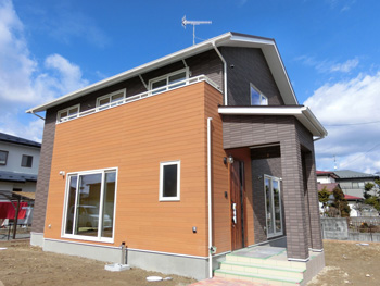 木目調サイディングと、綺麗なタイル調サイディングで存在感のある枠組壁工法の住宅。ヒートポンプ式床暖房採用。